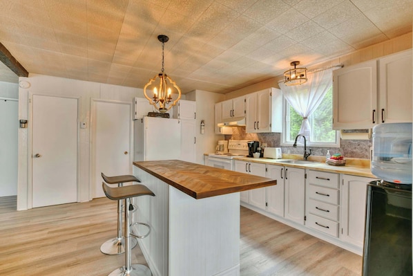 A modern kitchen with white cabinetry, a wooden island, and a bar stool.