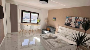 Ein modernes Wohnzimmer mit einem großen Bett, einem Essbereich und einem Fernseher.
