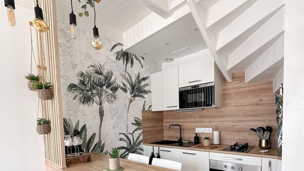 A modern kitchen with a wooden table, white chairs, and a built-in oven. - La Petite M (Tréméreuc)