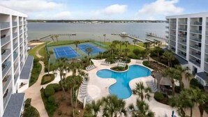 Un hotel con piscina, canchas de tenis y vista al agua.