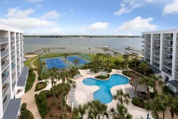 Un hotel con piscina, canchas de tenis y vista al agua.