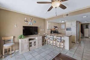 Una cocina moderna con una isla central, taburetes de bar y un ventilador de techo.