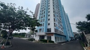 A tall residential building with a sign for 'Nikita Fried Chicken' on the ground floor. - Capital O 93961 Apartement Sentraland By Helen (Karawang)