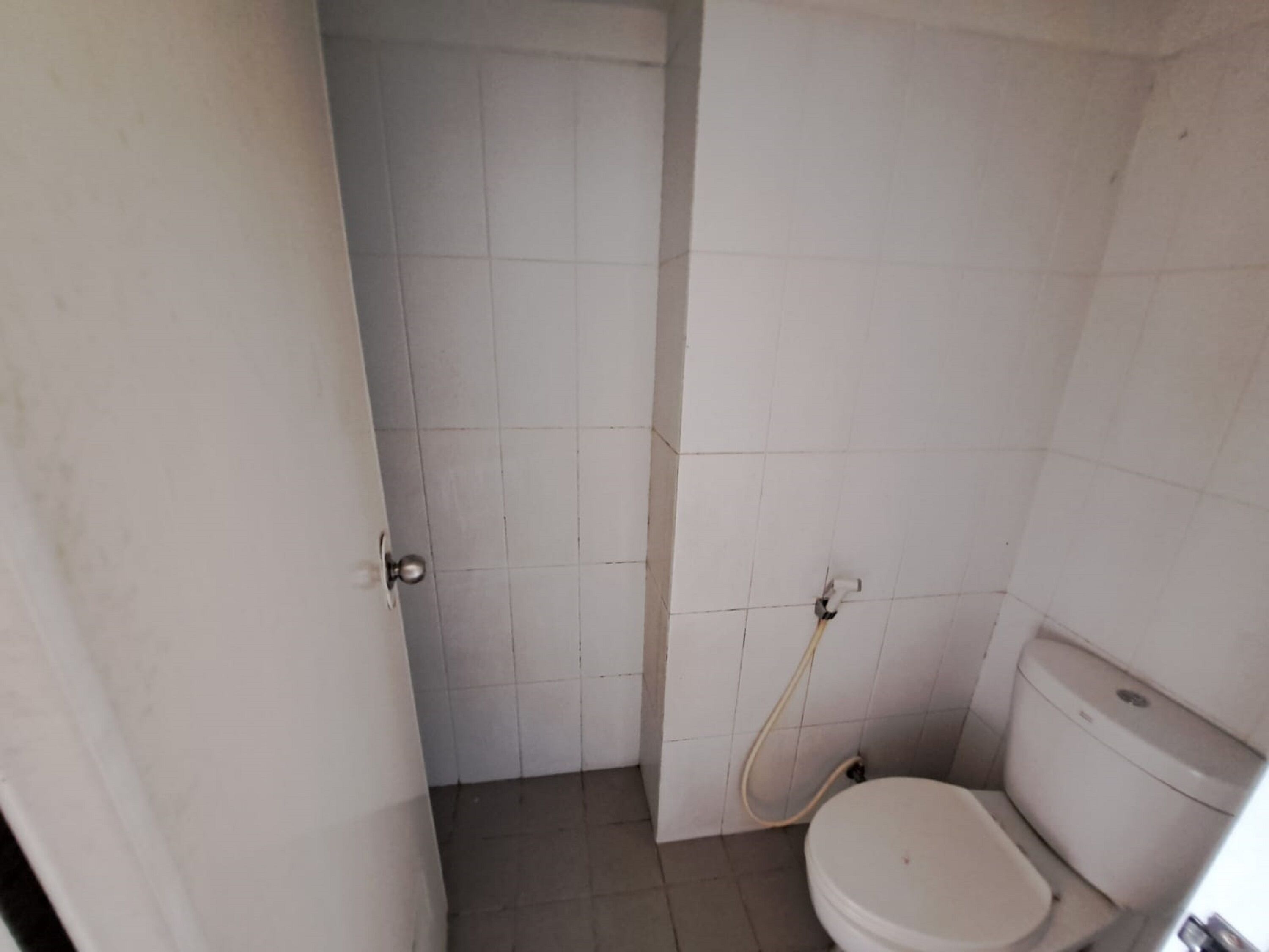 Une petite salle de bain simple, équipée de toilettes et d’une douche.