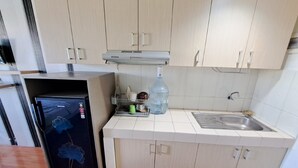 A compact kitchen with light-colored cabinets, a stainless steel sink, and a refrigerator. - Capital O 93961 Apartement Sentraland By Helen (Karawang)