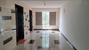 A hallway with a tiled floor, a door with a red mat, and a window with blinds. - Capital O 93961 Apartement Sentraland By Helen (Karawang)