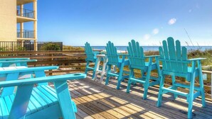 Una terraza de madera con sillas Adirondack turquesas y un edificio con balcones.