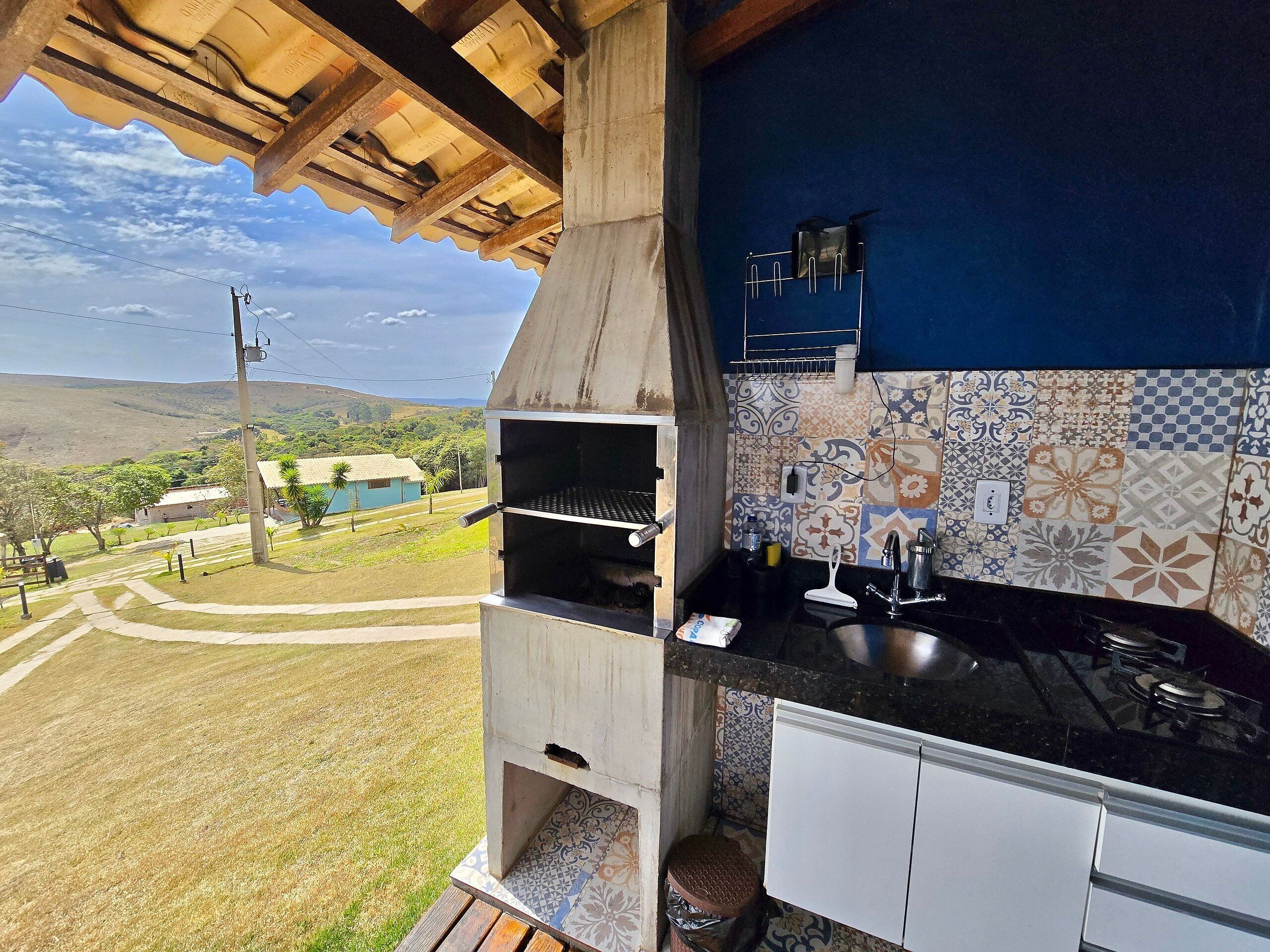 Een keuken met een ingebouwde grill, een spoelbak en uitzicht op een landelijk landschap.