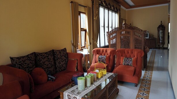 A living room with a red sofa, matching armchairs, a glass-top coffee table, and a patterned floor. - Hotel O Wisma Kost & Penginapan Afilia Buana Syariah (Tulungagung)