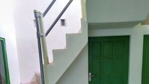A staircase leading to a green door, a small window, and a tiled floor with a patterned section. - Hotel O Wisma Kost & Penginapan Afilia Buana Syariah (Tulungagung)