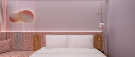 Una habitación de hotel moderna con una cama bien hecha, un cabecero estampado y un aplique de pared.