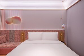 Ein modernes Hotelzimmer mit einem ordentlich bezogenen Bett, einem gemusterten Kopfteil und einer Wandleuchte.