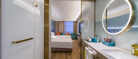 A hotel room with a large bed, a bathroom with a mirror and sink, and a view of the hotel lobby.