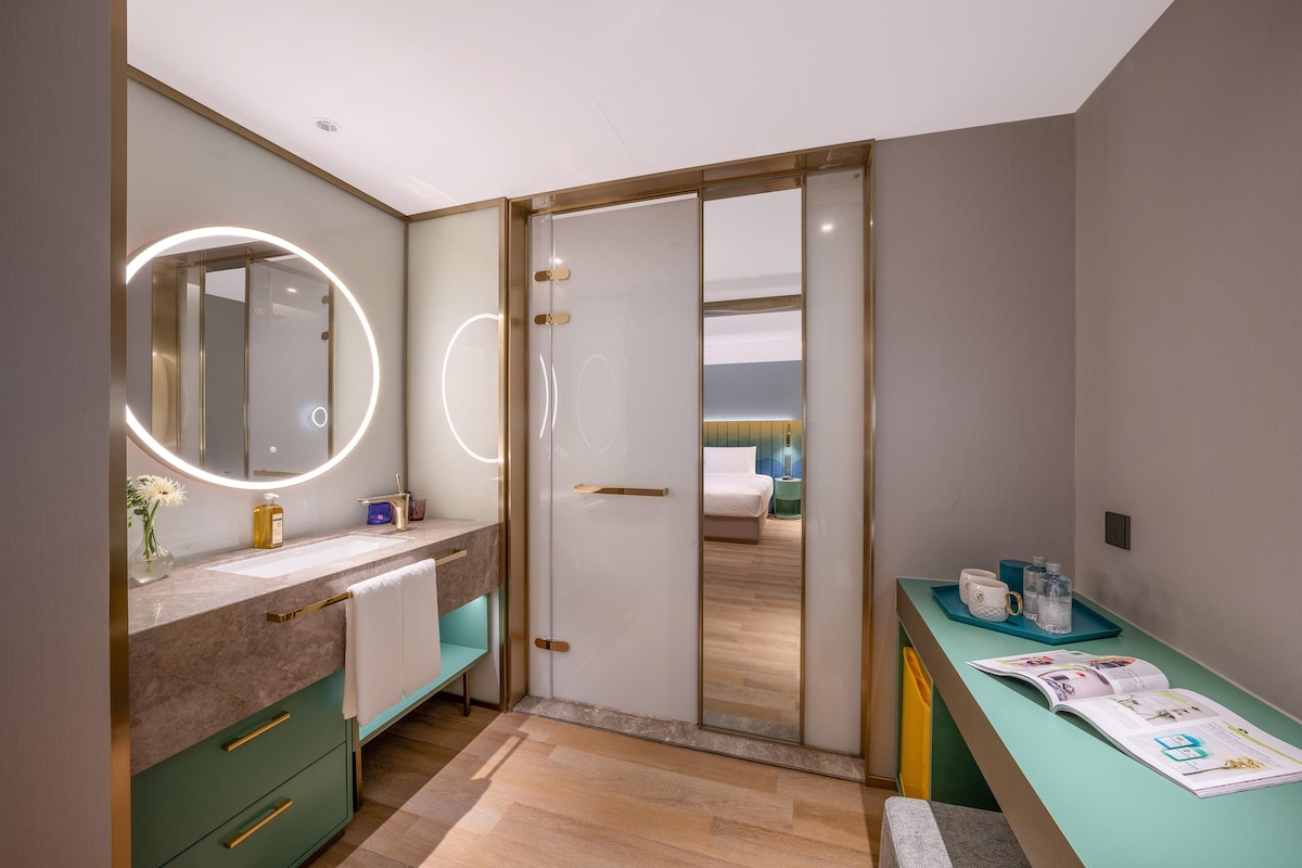 A modern bathroom with a vanity, mirror, and a shower area.