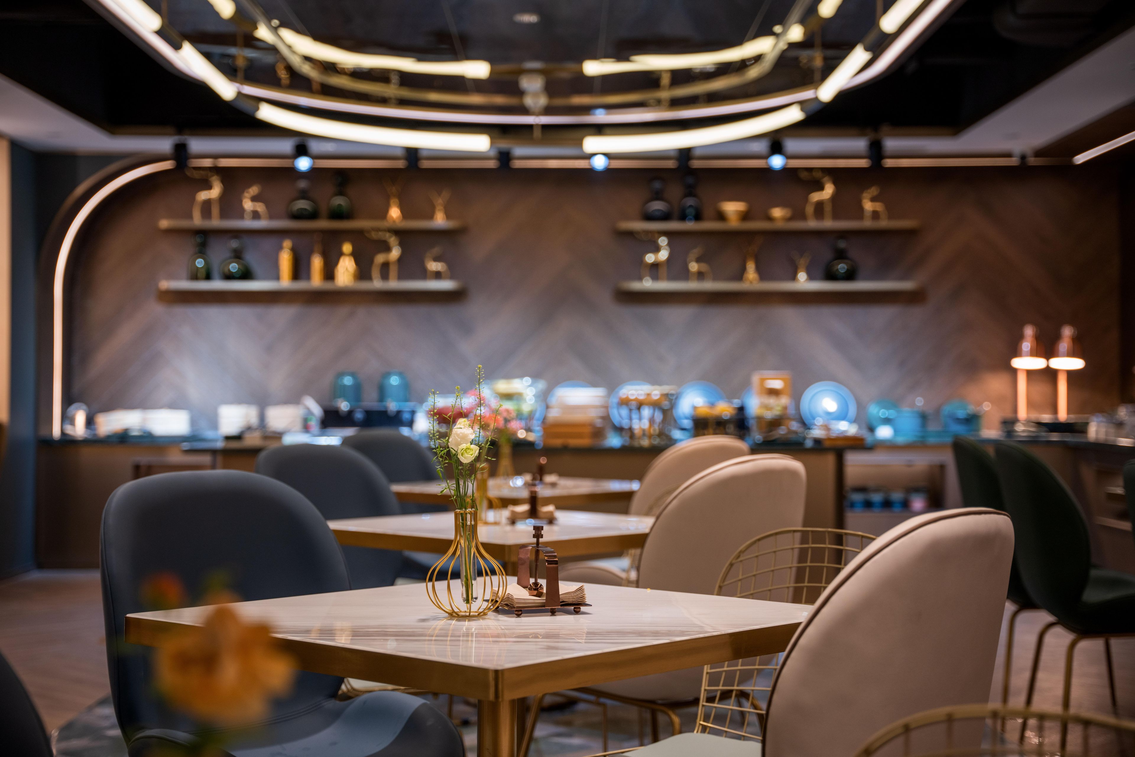 A restaurant with tables set for dining, a bar area, and shelves with bottles and glasses.