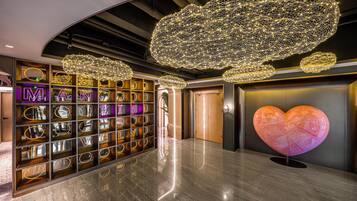A modern interior with a reflective floor, a large heart-shaped sculpture, and a wall of illuminated letters.