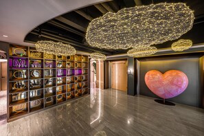 Ein modernes Interieur mit einem spiegelnden Boden, einer großen herzförmigen Skulptur und einer Wand aus beleuchteten Buchstaben.
