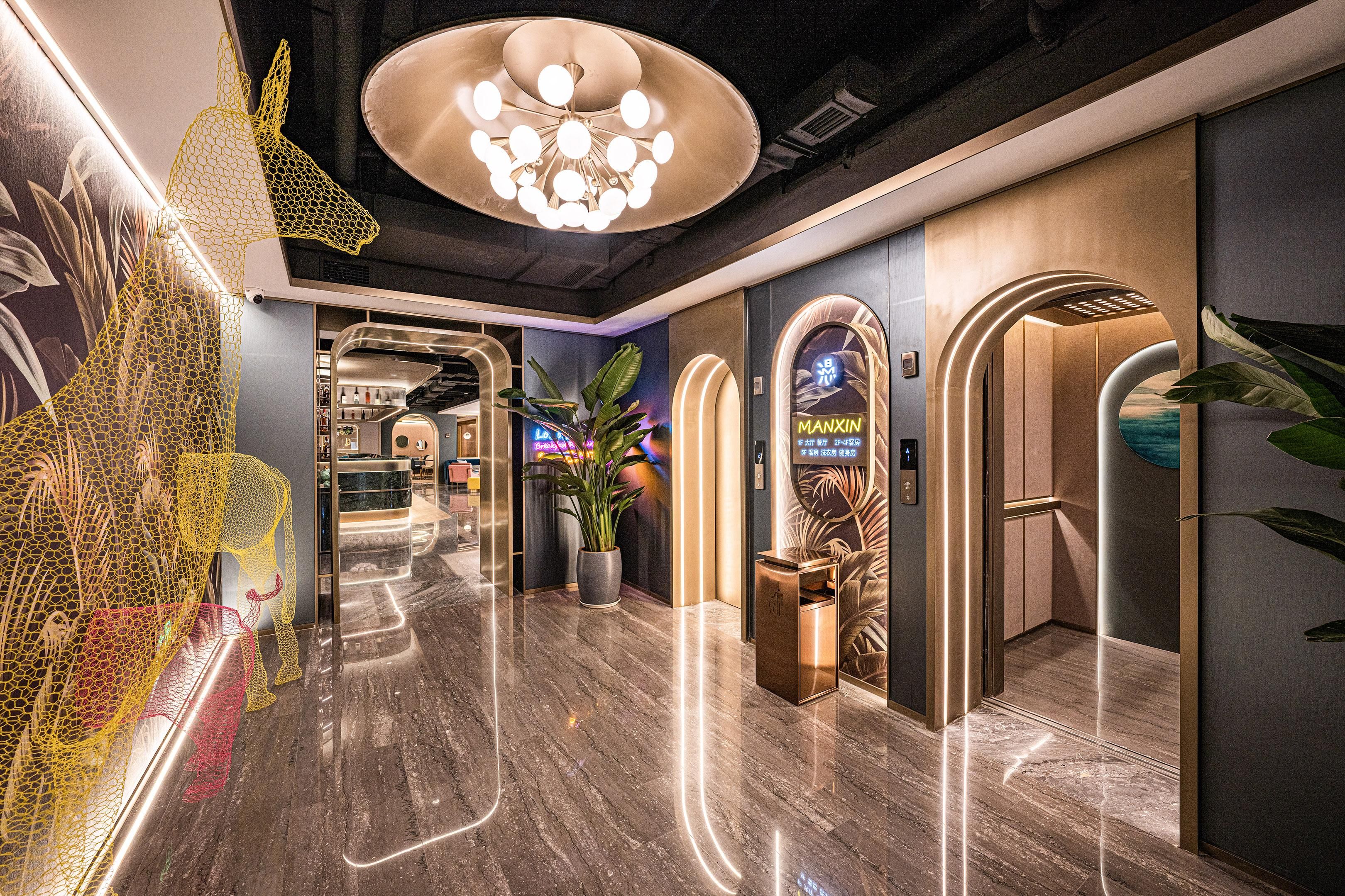 A modern hotel lobby with a marble floor, a large chandelier, and a reception desk.