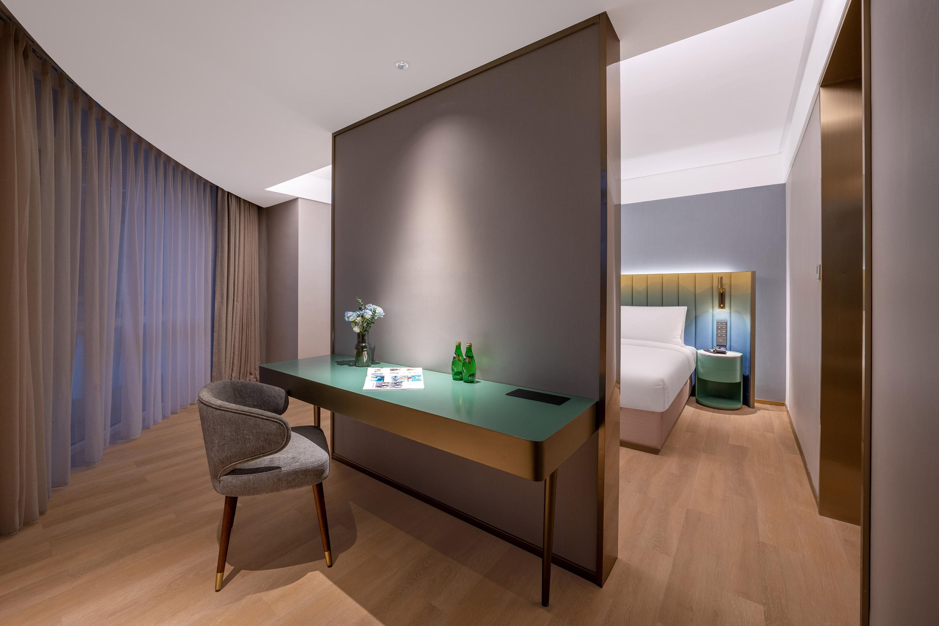 Une chambre d’hôtel moderne équipée d’un bureau, d’une chaise et d’un lit.