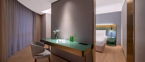 A modern hotel room with a desk, chair, and a bed.