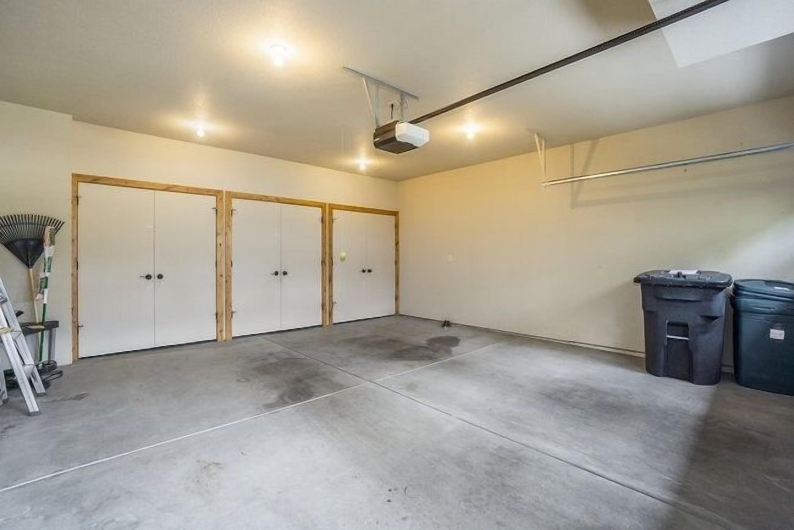Un grand garage doté d’un sol en béton, de portes en bois et d’un projecteur fixé au plafond.
