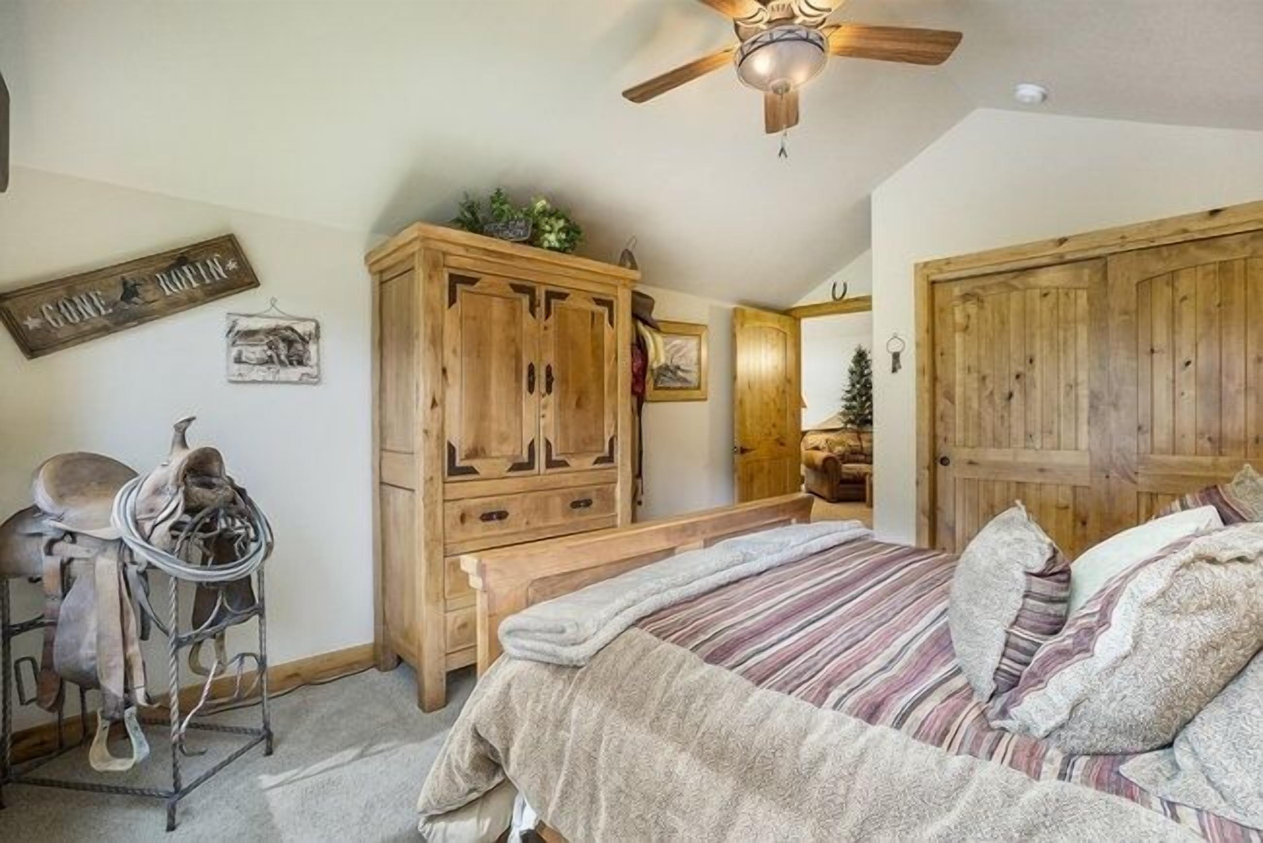 A bedroom with a bed, wooden wardrobe, and a ceiling fan.