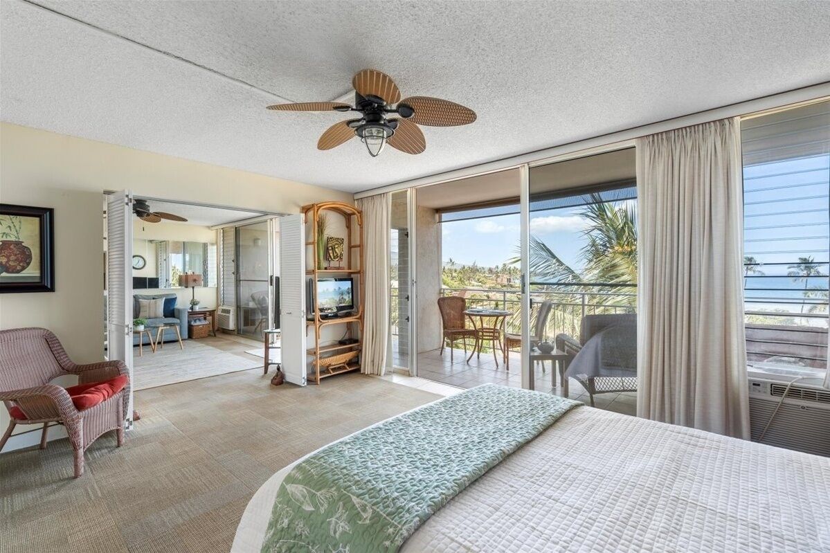 Une chambre d’hôtel avec un grand lit, un ventilateur de plafond, une télévision et un balcon donnant sur la plage.