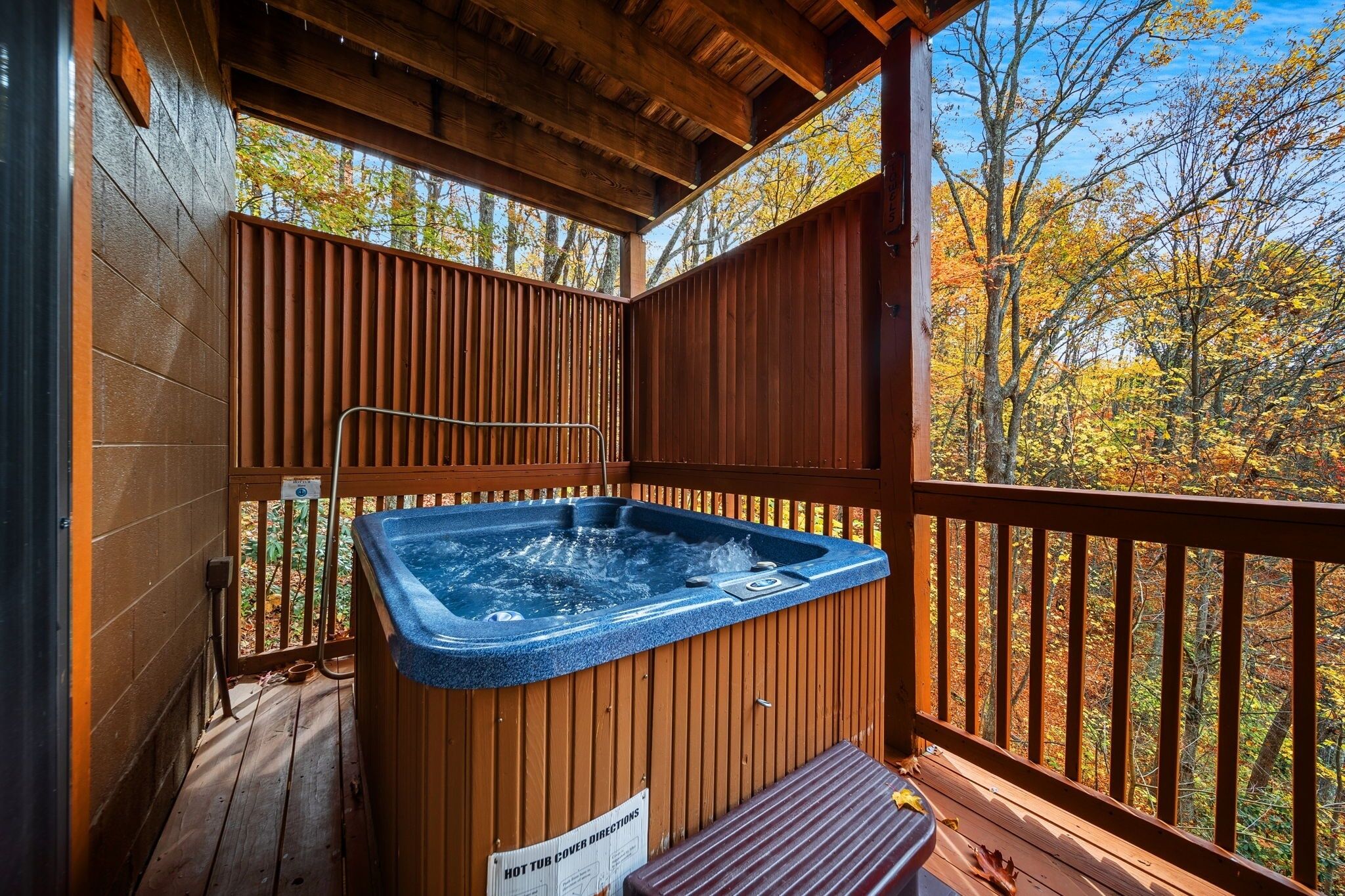 Ein Whirlpool auf einer Holzterrasse mit Blick auf herbstliche Bäume.