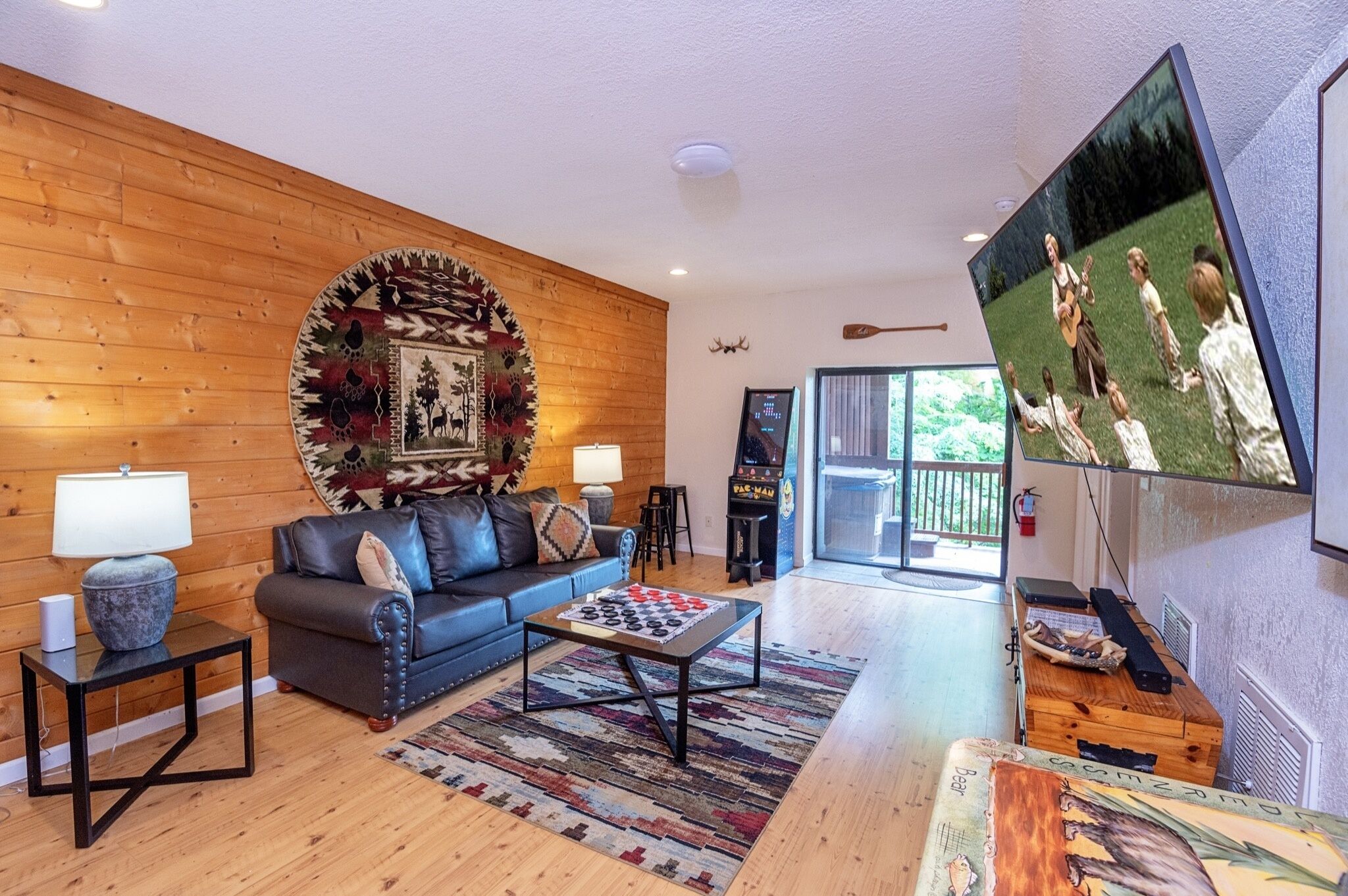 A cozy living room with a wooden wall, a sofa, a coffee table, a TV, and a fireplace.