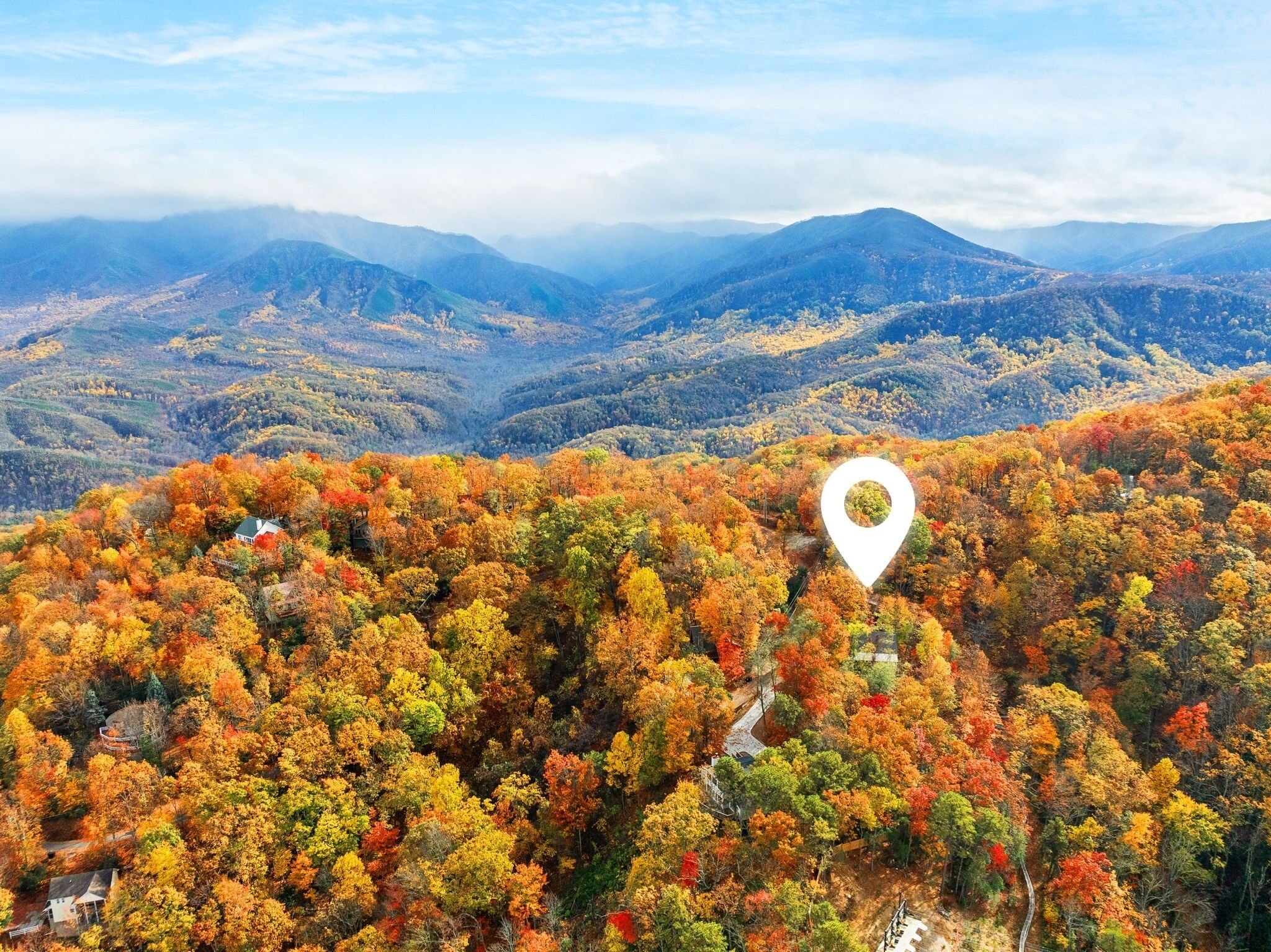 Eine gebirgige Landschaft mit Herbstlaub und einem weißen Standortmarker.