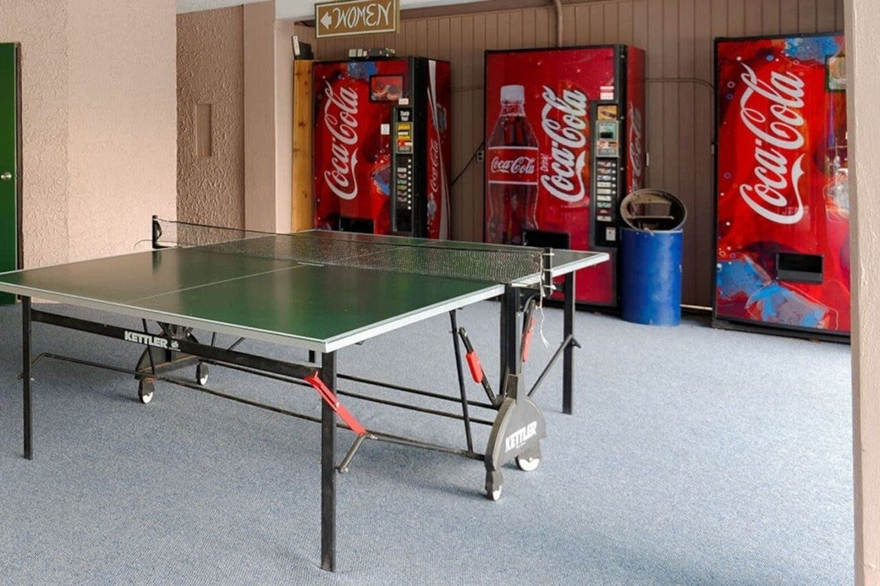 A ping pong table with Coca-Cola vending machines in the background.