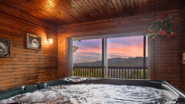 Una cabaña de madera con hidromasaje y vistas panorámicas a la montaña.