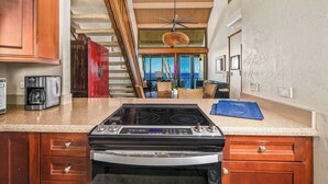 Una cocina con estufa, horno y cafetera. Una escalera conduce a un balcón con vistas.
