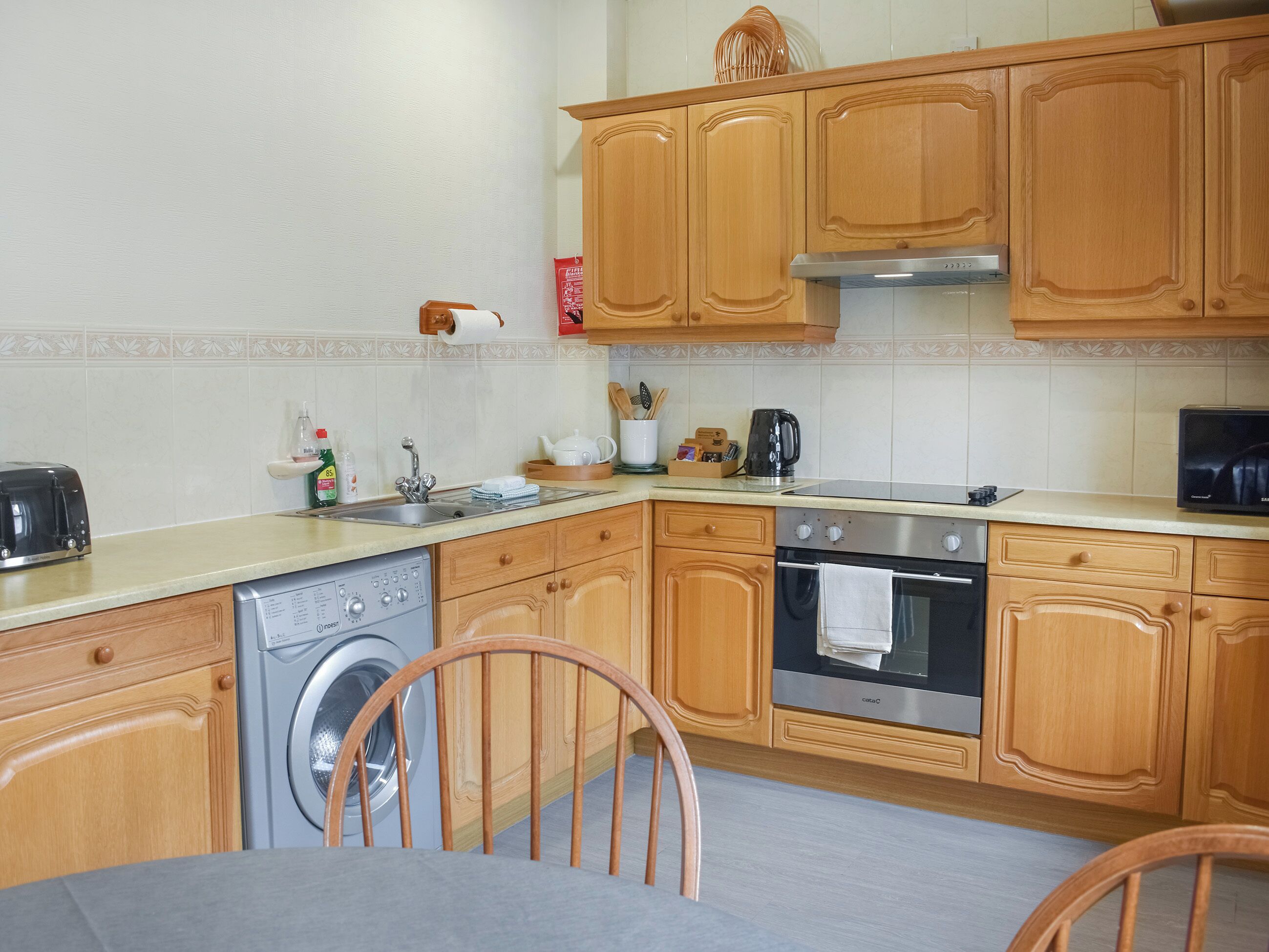 Una cocina con armarios de madera, lavadora, estufa y microondas.