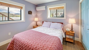 A bedroom with a bed, two bedside tables, a window, and a door. - Lakefront Oroville Paradise: Private Beach & Dock! (Oroville)