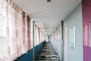 A long hallway with patterned curtains, a patterned carpet, and framed pictures on the walls. - Qingjiang Express Hotel (Zhangshu)