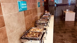 Una linea di buffet con diverse opzioni di cibo, una parete piastrellata con cartelli e un'area salotto con tavoli e sedie.