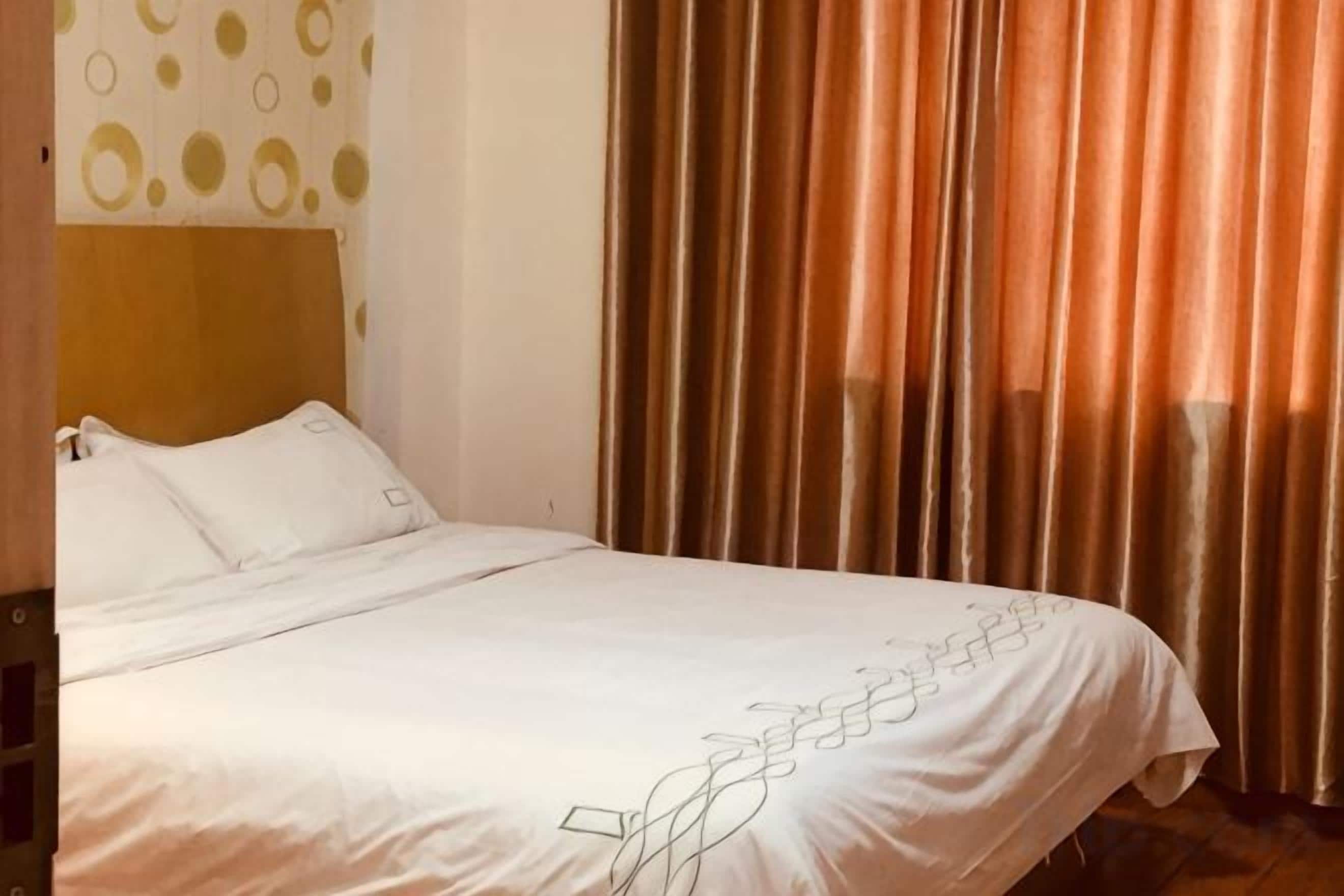 A hotel room with a bed, curtains, and a headboard.