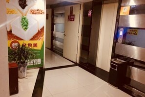A hotel lobby with a reception desk, a potted plant, a poster, and a trash bin. - Qingjiang Express Hotel (Zhangshu)