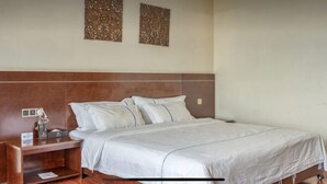 Una camera d'albergo con un letto, un comodino, una lampada e due decorazioni a parete.