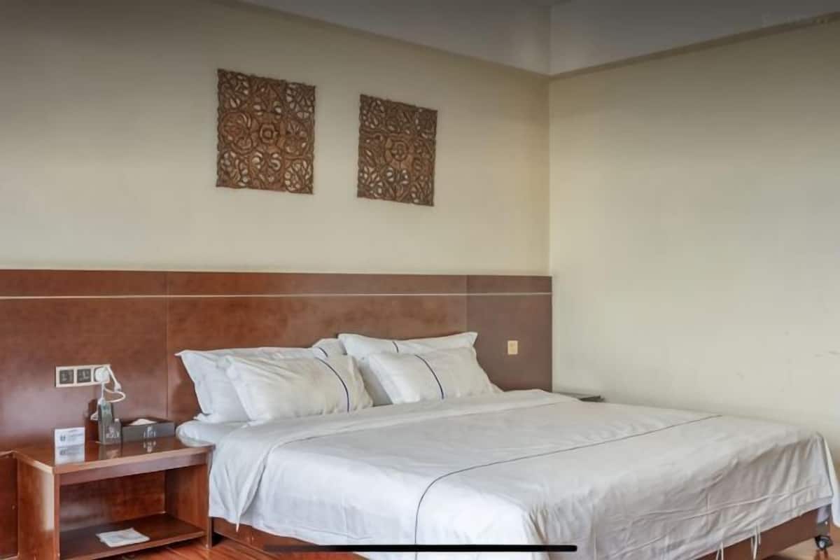 A hotel room with a bed, nightstand, lamp, and two wall decorations.