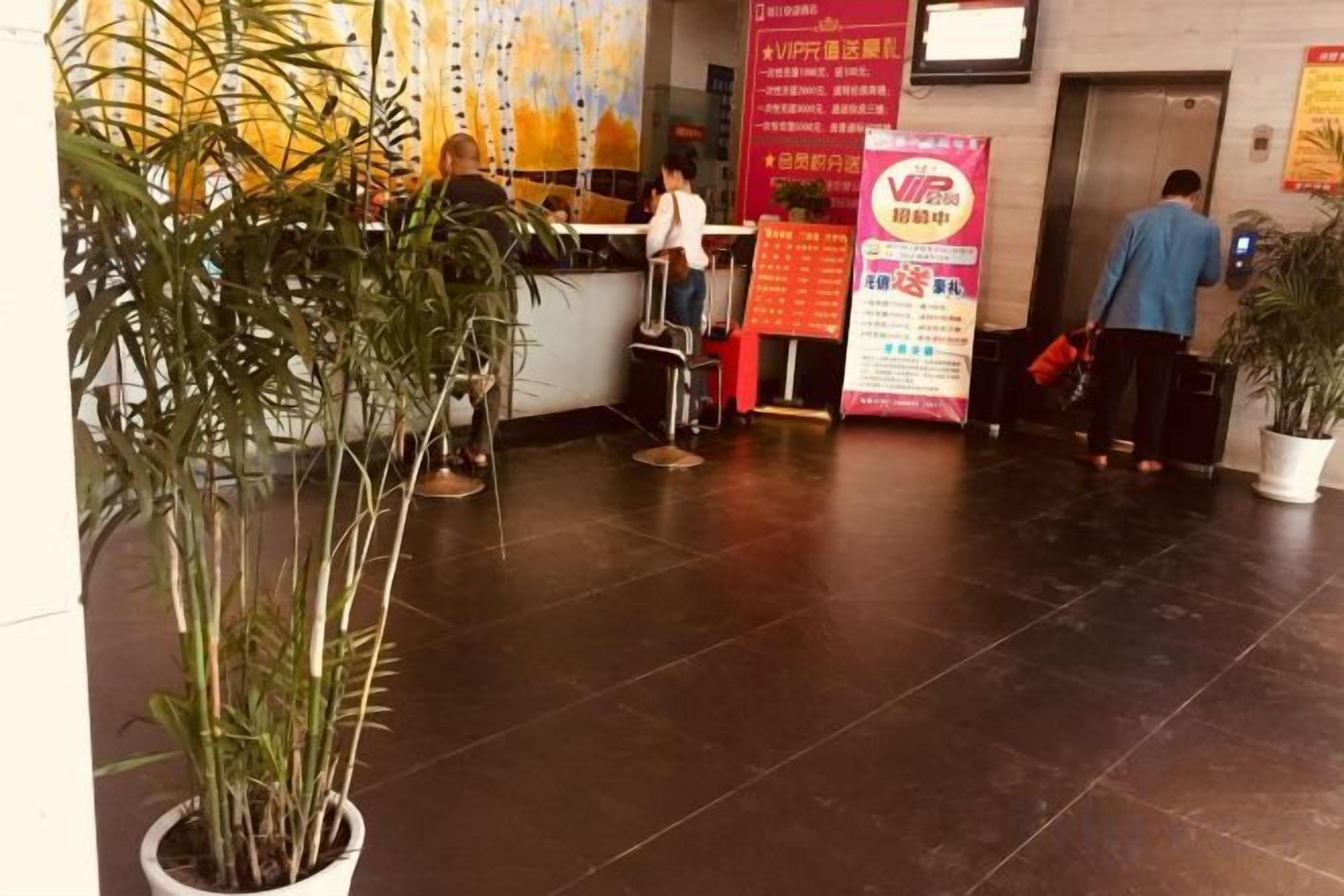 A reception area with a counter, potted plants, and a poster on the wall.