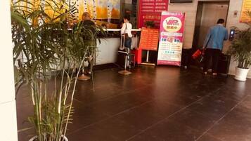A reception area with a counter, potted plants, and a poster on the wall.