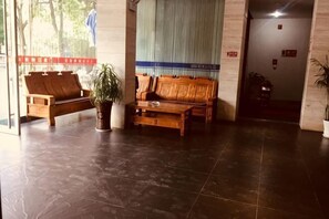 A lobby with a wooden sofa, a coffee table, and a potted plant. - Qingjiang Express Hotel (Zhangshu)