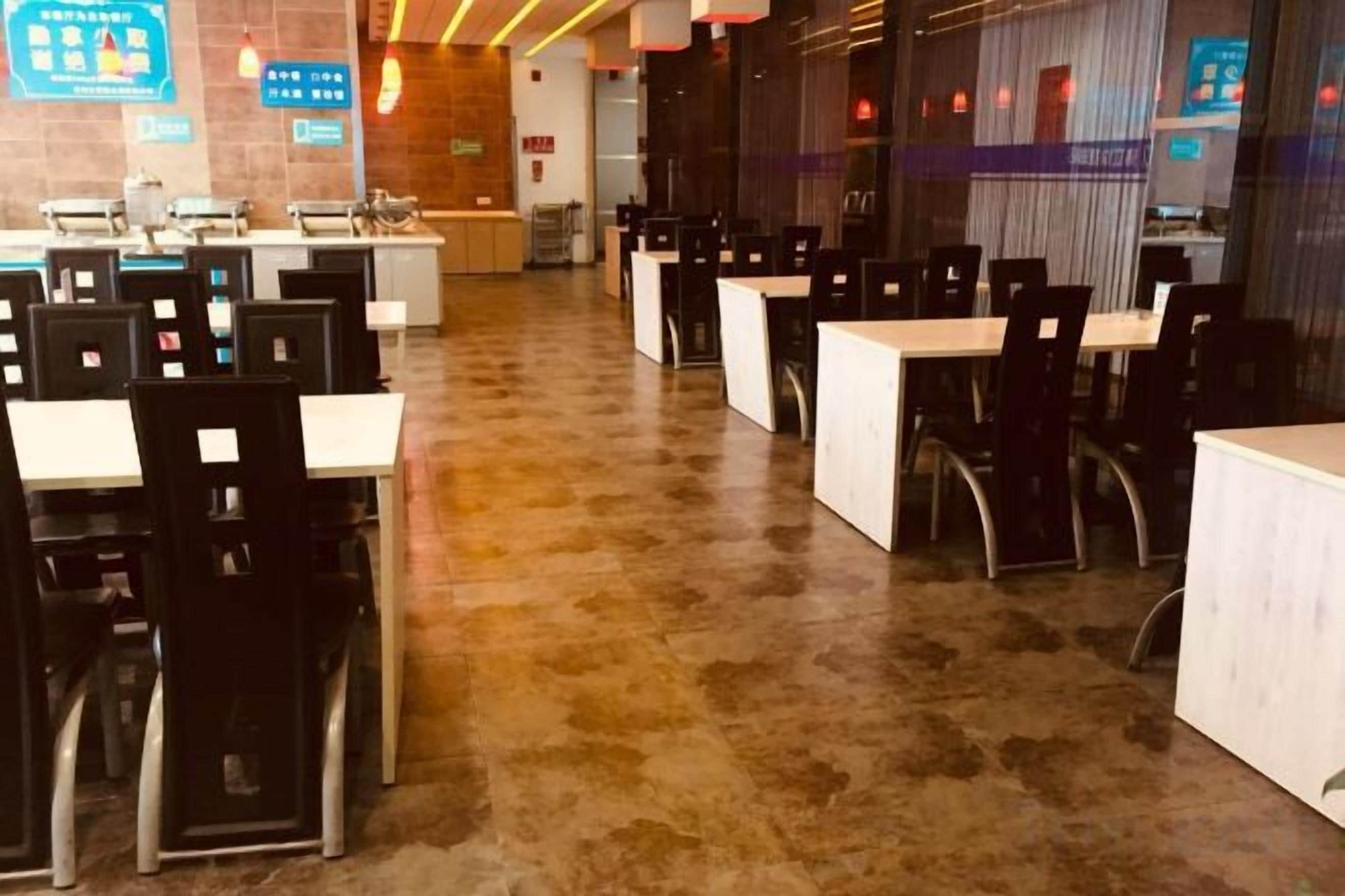 A restaurant with multiple tables and chairs, a tiled floor, and a counter area.