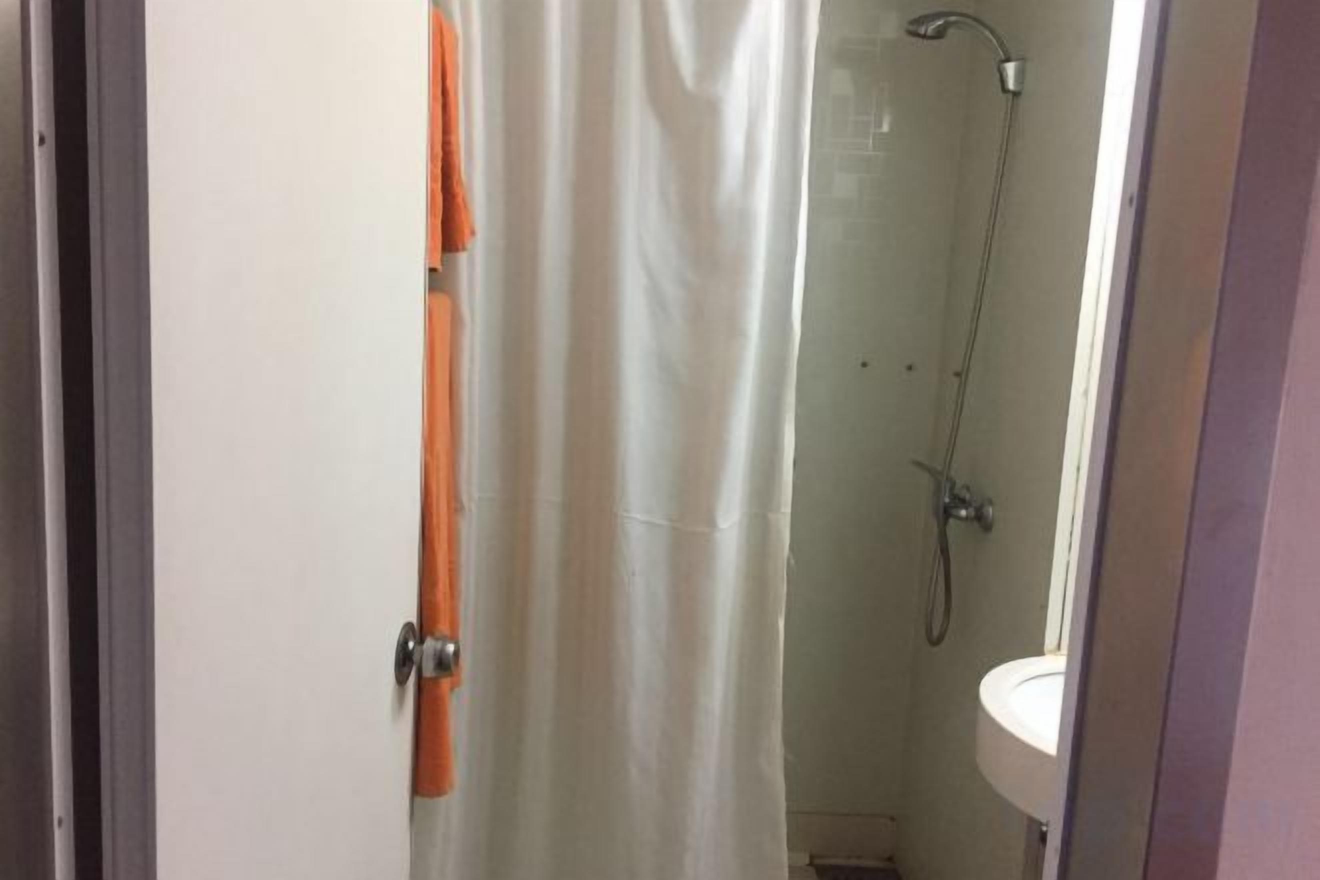 A bathroom with a shower, a sink, and a door.