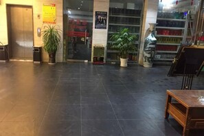 A lobby with a door, potted plants, a table, and a poster on the wall. - Qingjiang Express Hotel (Zhangshu)