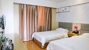 Habitación de hotel con dos camas, un escritorio con tetera y set de té, televisión y aire acondicionado.