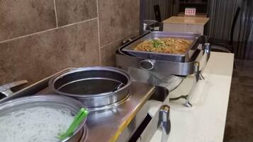 A buffet setup with various food items and serving utensils.
