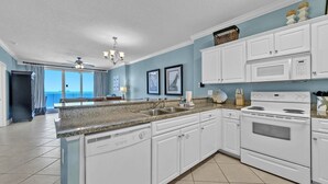 A kitchen with white cabinets, a granite countertop, a built-in oven, and a view to the outside.
